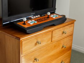 A television and gaming joystick on a drawer unit at Manaia Magic - Tairua Holiday Home, Tairua