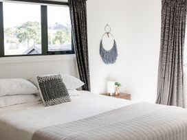 A bedroom with a bed, pillows, and curtains at Manaia Magic - Tairua Holiday Home, Tairua