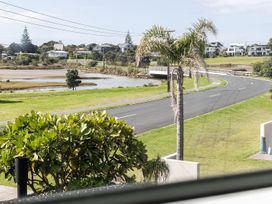 A view of a road and water with houses in the background at Manaia Magic - Tairua Holiday Home, Tairua