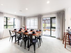 A dining room with a large table set for meals at Manaia Magic - Tairua Holiday Home in Tairua