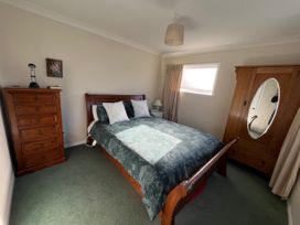 A bedroom with a bed and wooden furniture at Le Solterre - Akaroa Holiday Home, Akaroa