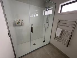 A shower with glass doors and a towel rack at Beachy Keen - Whangamata Holiday Apartment Whangamata