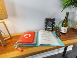 A tabletop with a lamp, folder, book, snack, wine bottle, and vase at Bliss on Barratt - Blenheim