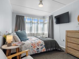 A bedroom with a bed, side table, and television at Bliss on Barratt - Blenheim Holiday Home, Blenheim