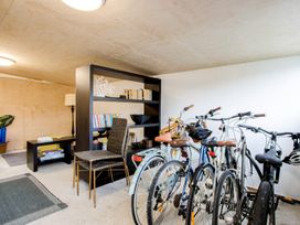 A room with bicycles parked next to a black shelf holding books and decor at Bird and Fish - Napier Holiday Home in Napier