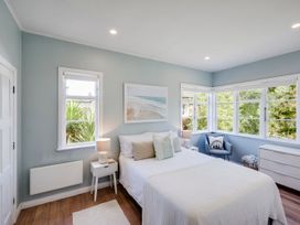 A bedroom with a bed and windows at Bird and Fish - Napier Holiday Home, Napier