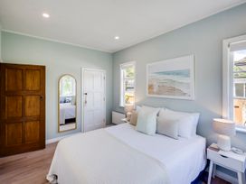A bedroom with a bed and windows at Bird and Fish - Napier Holiday Home in Napier