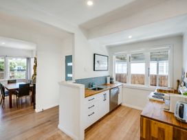 A kitchen featuring sink, stove, and dining table at Bird and Fish - Napier Holiday Home, Napier