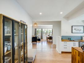 A living room with a display cabinet and seating area at Bird and Fish - Napier Holiday Home in Napier