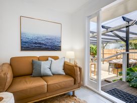A living room with a sofa and door leading to outdoor dining at Bird and Fish - Napier Holiday Home Napier