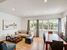 A living room with a sofa, coffee table, and dining table at Bird and Fish - Napier Holiday Home Napier