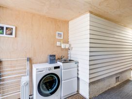 A laundry room with a washing machine and sink at Bird and Fish - Napier Holiday Home in Napier