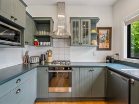 A kitchen with cabinets, stove, oven, microwave and sink at Kokomea House - Wanaka