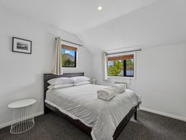 A bedroom with a bed and windows at Kokomea House - Wanaka