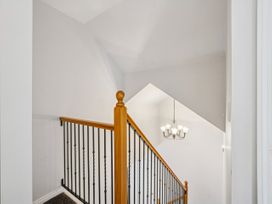 A staircase with a railing and chandelier at Kokomea House - Wanaka