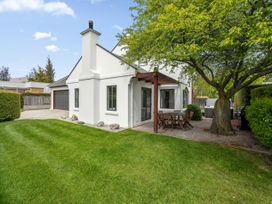 A garden with a house, tree, and dining set at Kokomea House - Wanaka