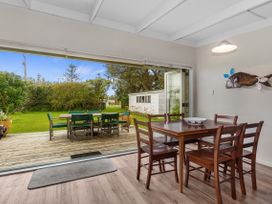 A dining room with a view of the backyard at Coastal Cove – Waipu Cove