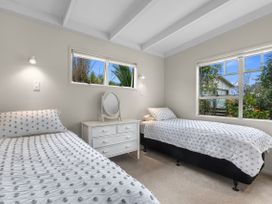 A bedroom with two beds and a dresser at Coastal Cove – Waipu Cove