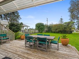 An outdoor deck with a table and chairs at Coastal Cove – Waipu Cove