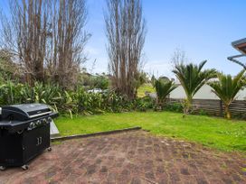 An outdoor area with a barbecue grill and grass at Coastal Cove – Waipu Cove
