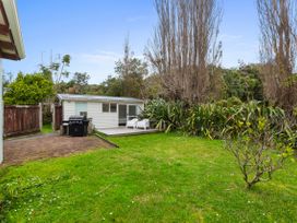 A garden with a deck and grill at Coastal Cove – Waipu Cove