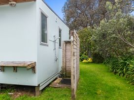 An outdoor shower next to a small house in a garden at Coastal Cove – Waipu Cove