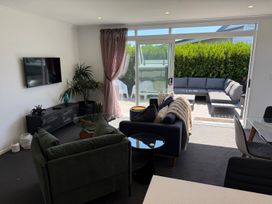 A living room with a television and seating leading to outdoor space at Treasure on Tuscan - Martinborough
