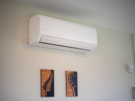 An air conditioning unit and wooden wall art in a living room at Fiordland Getaway - Te Anau Holiday Home Fiordland
