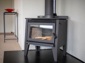 A wood stove and a metal stand in a living room at Fiordland Getaway - Te Anau Holiday Home in Fiordland