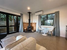 A living room with a wood stove and dining table at Bushside Cottage - Akaroa Holiday Home