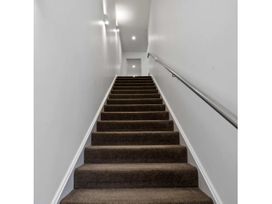 A staircase with a handrail and door at Lakeview Luxury - Taupo Holiday Apartment Taupo Central