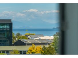 A view of water and buildings with mountains and clouds at Lakeview Luxury - Taupo Holiday Apartment in Taupo Central