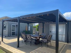 A patio with a table and chairs under a pergola at Kõpuha on Rangiora - Matarangi