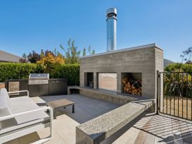 An outdoor living area with a barbecue grill and a concrete fireplace at Casa Central - Wanaka Holiday Home in Wanaka