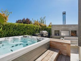 A hot tub next to an outdoor kitchen with a barbecue grill at Casa Central - Wanaka Holiday Home in Wanaka