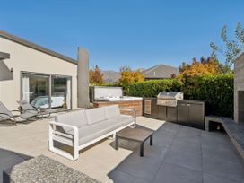 An outdoor patio with a sofa, coffee table, grill, hot tub, and sun loungers at Casa Central - Wanaka Holiday Home, Wanaka