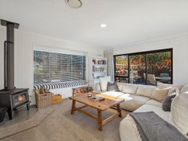 A living room with a wood stove and sofa at Frankton Favourite - Queenstown Holiday Home in Queenstown