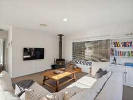 A living room with a sofa, coffee table, and television at Frankton Favourite - Queenstown Holiday Home, Queenstown