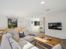 A living room with a sofa, coffee table, and dining area at Frankton Favourite - Queenstown Holiday Home, Queenstown