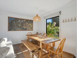 A dining room with a table and wooden chairs at Frankton Favourite - Queenstown Holiday Home in Queenstown