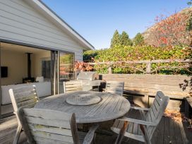 An outdoor area with a wooden table and chairs near a barbecue at Frankton Favourite - Queenstown Holiday Home Queenstown
