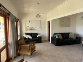 A living room with sofas and an armchair at The Beach House - Paihia