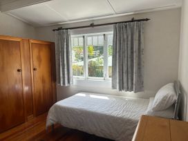 A bedroom with a bed and wardrobe at The Beach House - Paihia Holiday Home