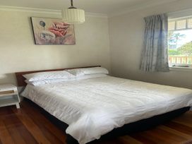 A bedroom with a bed and a nightstand at The Beach House - Paihia