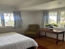 A bedroom with a bed and a table at The Beach House - Paihia Holiday Home