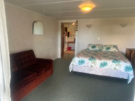 A bedroom with a bed and sofa at The Beach House - Paihia Holiday Home