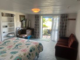 A bedroom with a bed, sofa, and sliding door at The Beach House - Paihia Holiday Home