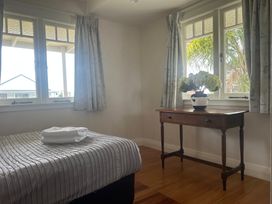 A bedroom with a bed and table at The Beach House - Paihia Holiday Home