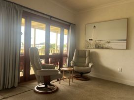 A living room with chairs and a side table at The Beach House - Paihia Holiday Home