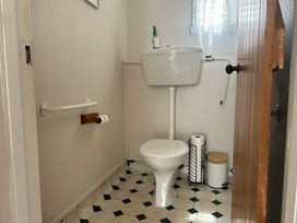 A bathroom with a toilet and grab bar at The Beach House - Paihia Holiday Home
